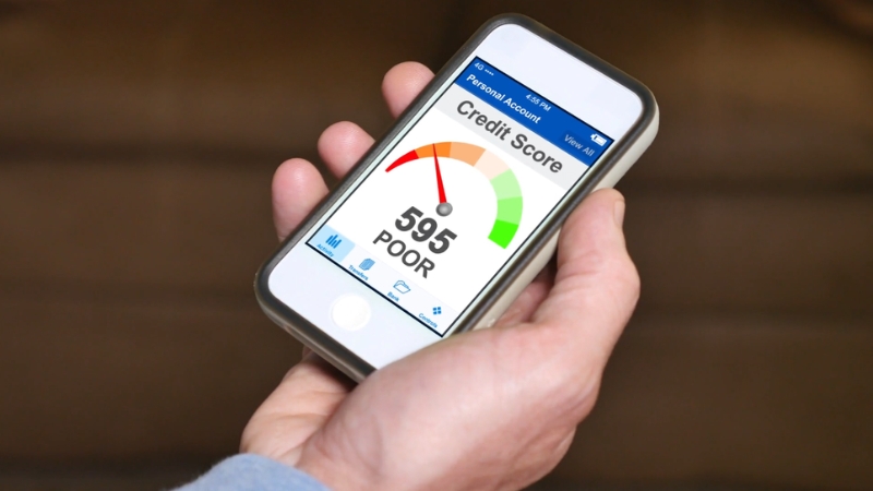 A phone shows a 595 credit score labeled poor after debt settlement