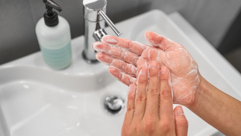 Hands covered in soap are washed under a faucet as part of a mindful hand washing routine to ease anxiety