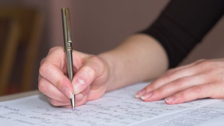 A person writing answers on paper during preparation for an oral and written math test