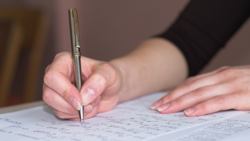 A person writing answers on paper during preparation for an oral and written math test